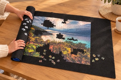Tapis à puzzle gris à moitié enroulé avec les pièces de puzzle en place sur le rouleau, puzzle en cours sur la partie déroulée