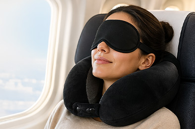 Femme portant un coussin cervical à mémoire de forme et un masque de sommeil en avion