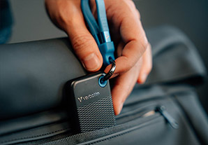 Disque dur SSD Verbatim noir accroché à un sac à dos grâce à une dragonne bleue. Pratique pour le transport.