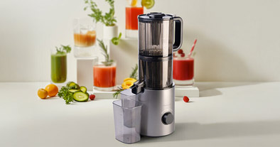 extracteur avec en arrière plan des verres remplis de jus de légumes et fruits